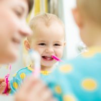 Infant with baby teeth learning how to brush