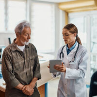 general practitioner and her senior patient using digital tablet